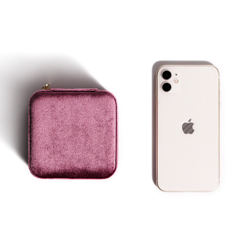 Closed pink velvet travel jewellery box next to a phone for size